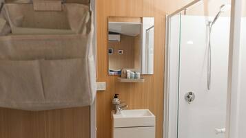 A bathroom with a shower, a sink, a mirror, and a towel rack.