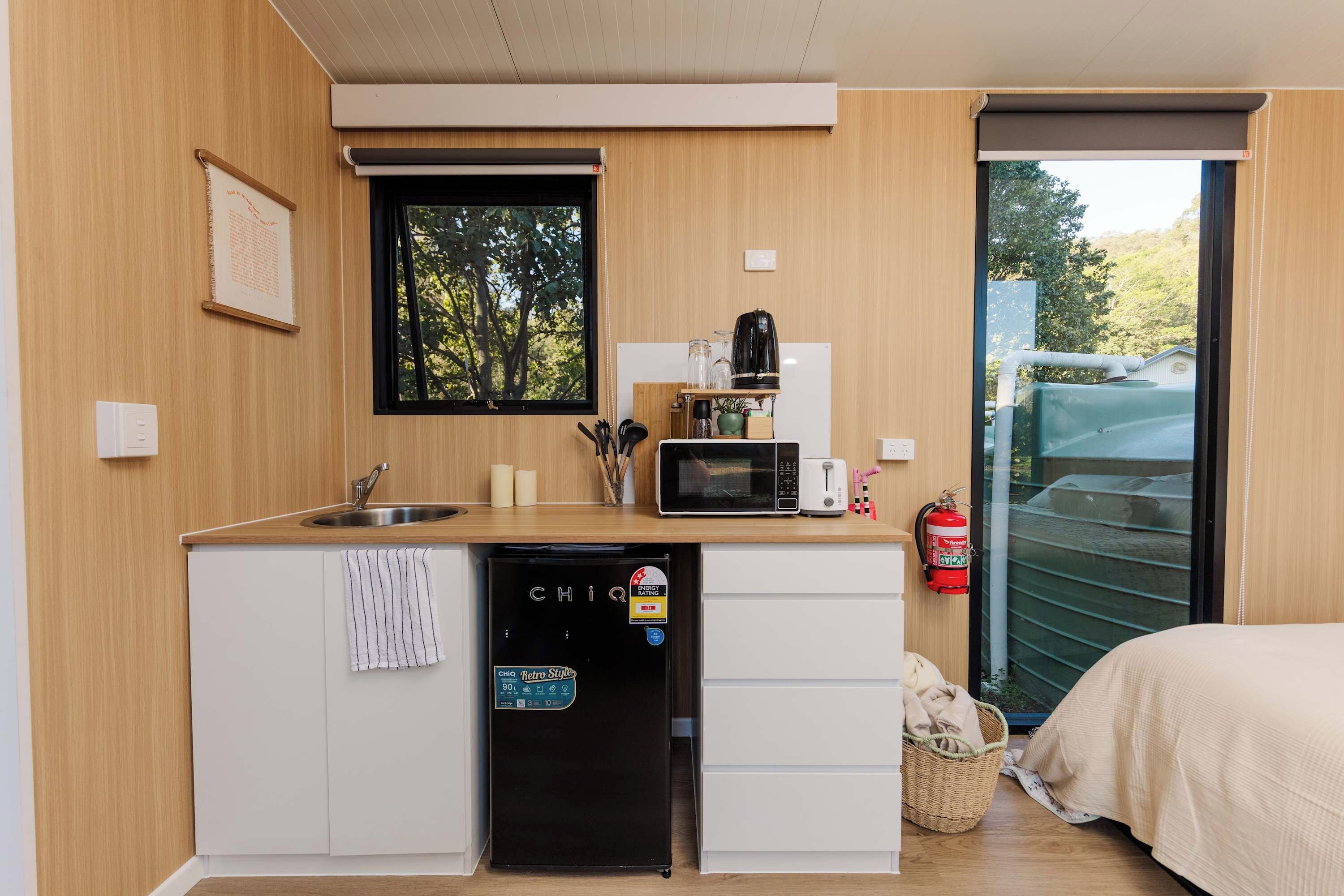 A compact kitchenette with a sink, microwave, toaster, and a small refrigerator.