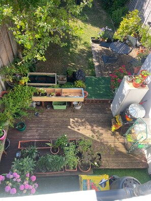 A wooden deck with potted plants, a wooden bench, and a small table. - Stylish Private Room in Croydon With Free Street Parking (London)