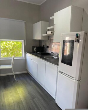 A modern kitchen with white cabinets, a black countertop, and a built-in refrigerator. - Stylish Private Room in Croydon With Free Street Parking (London)