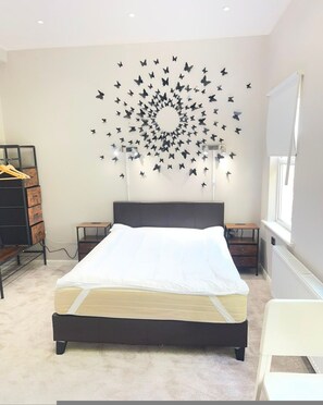 A bedroom with a bed, a dresser, a desk, and a wall-mounted light fixture. - Stylish Private Room in Croydon With Free Street Parking (London)