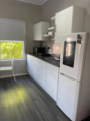 Eine moderne Küche mit weißen Schränken, einer schwarzen Arbeitsplatte und einem eingebauten Kühlschrank.