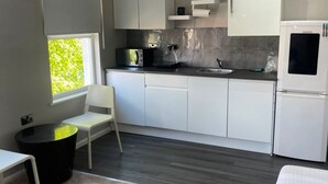A modern kitchen with white cabinets, a black countertop, and a refrigerator. - Bright Double Room in Croydon Free Street Parking (London)
