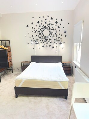 Ein Schlafzimmer mit einem Bett, einer Kommode, einem Schreibtisch und einer Wand mit Schmetterlingsstickern.