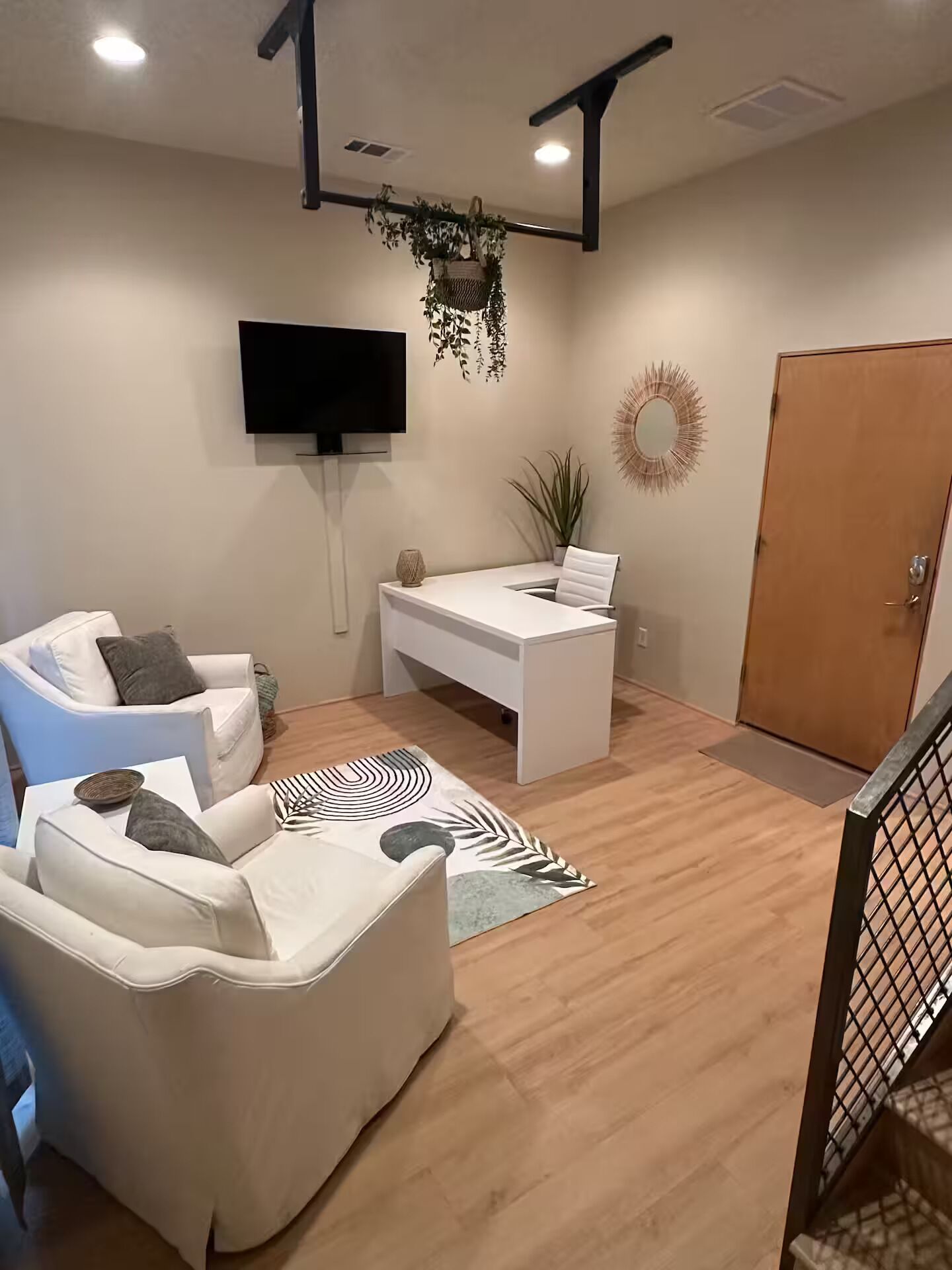Un salon moderne avec un canapé blanc, un bureau blanc et un téléviseur fixé au mur.