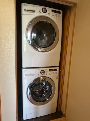A double-door laundry room with two stacked washing machines. - Silver Lofts (Albuquerque)