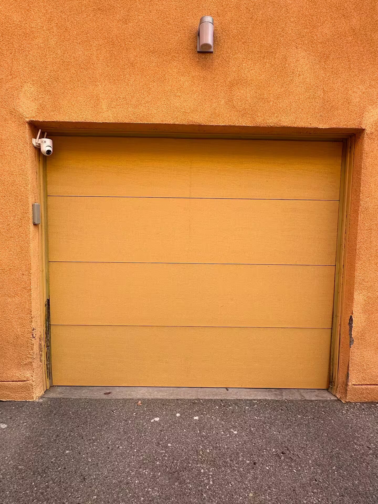 A closed garage door with a security camera above it.
