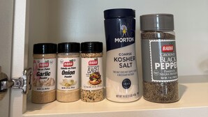 En hylde med forskellige krydderiglas, blandt andet hvidløgspulver, løgpulver, bagel-krydderi, kosher salt og sort peber.