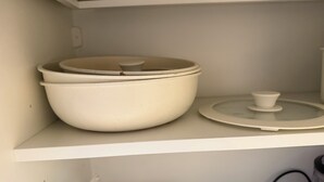 En køkkenhylde med hvide keramikkrukker og låg.