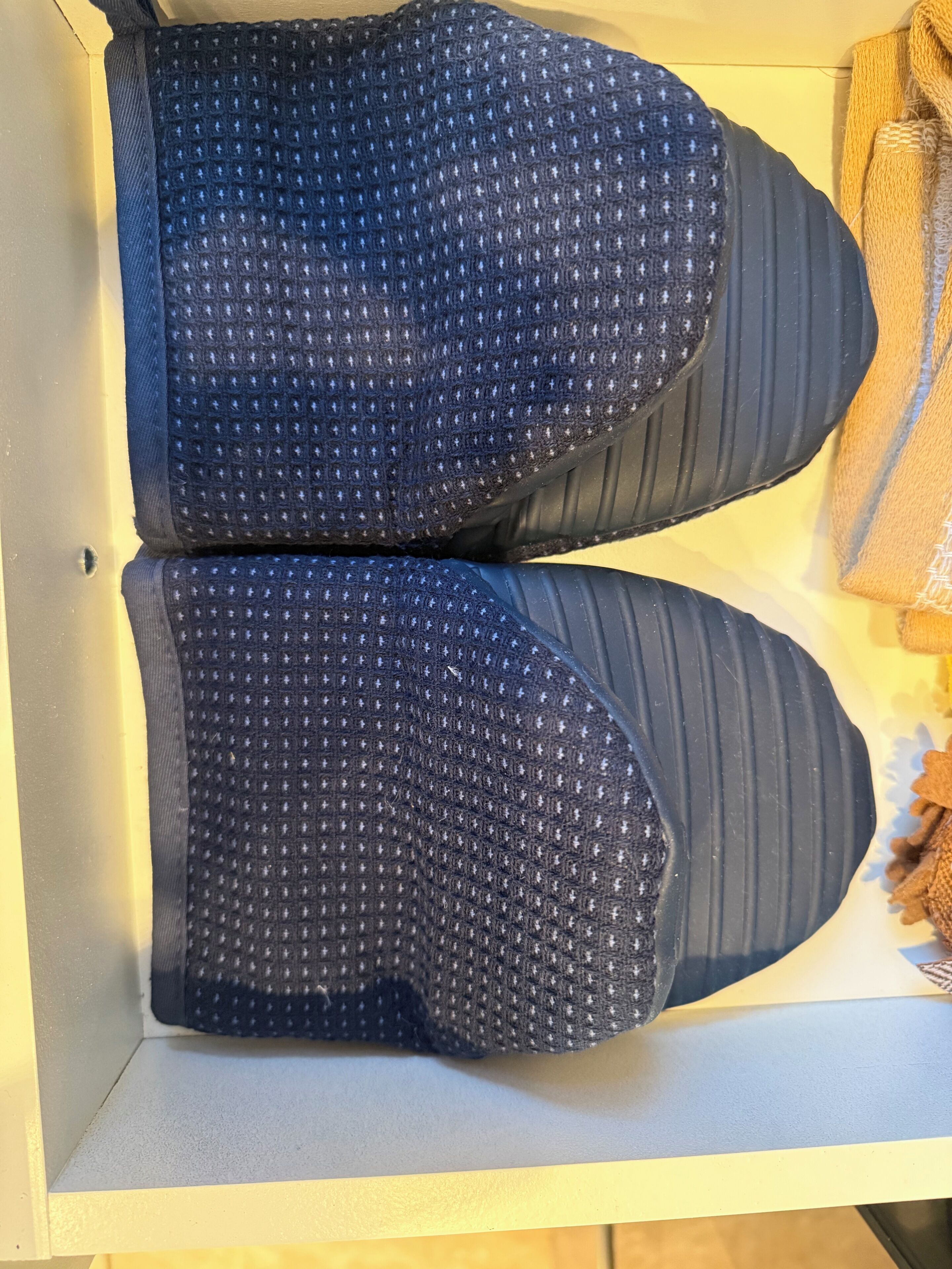 A pair of dark blue, textured shoes with a ribbed sole, placed on a light-colored surface.