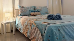 Een slaapkamer met een bed, een nachtkastje, een lamp, een wandairconditioner en twee decoratieve wandobjecten.