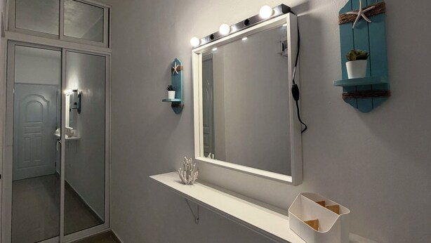 Een badkamer met een grote spiegel, wastafel en wandlampen.