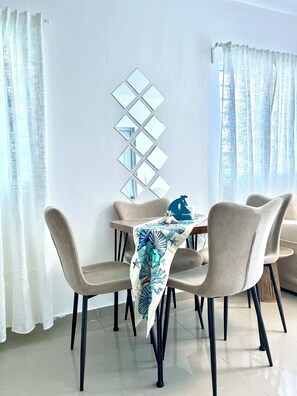 A dining area with a table set for four, a decorative mirror on the wall, and a view through the window. - The Best Location in Bayahibe (Bayahíbe)