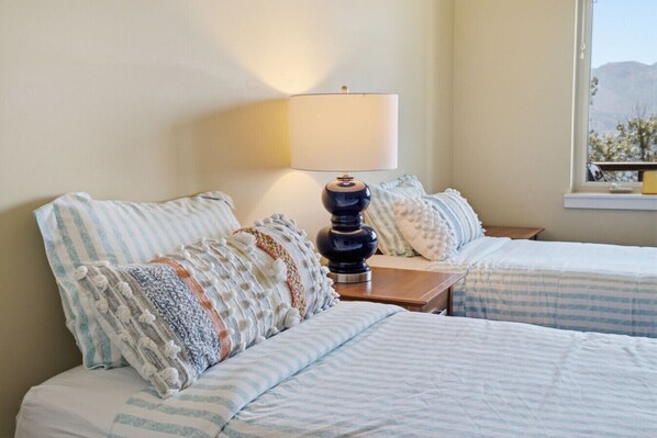A room with two beds, a lamp, and a window with a view.