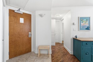 Ein Flur mit einer Holztür, einem kleinen Holzschemel, einem türkisblauen Schrank und einem gerahmten Bild an der Wand.