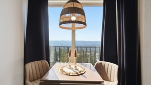 En balkon med et bord, stole, en dekorativ lampe og udsigt til bjergene.