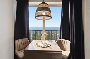 A balcony with a table, chairs, a decorative lamp, and a view of the mountains. - Ski-In/Ski-Out Studio | Mountain Views (Big White Mountain)