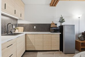 A modern kitchen with wooden cabinets, a stainless steel refrigerator, and a small plant on the counter. - Ski-In/Ski-Out Studio | Mountain Views (Big White Mountain)