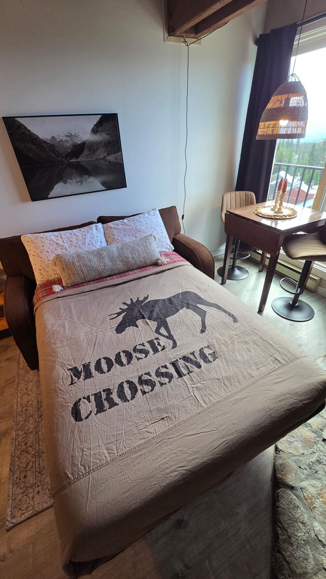 Un lit orné d’un motif représentant un élan, et la couverture de lit porte l’inscription « MOOSY CROSSING ».