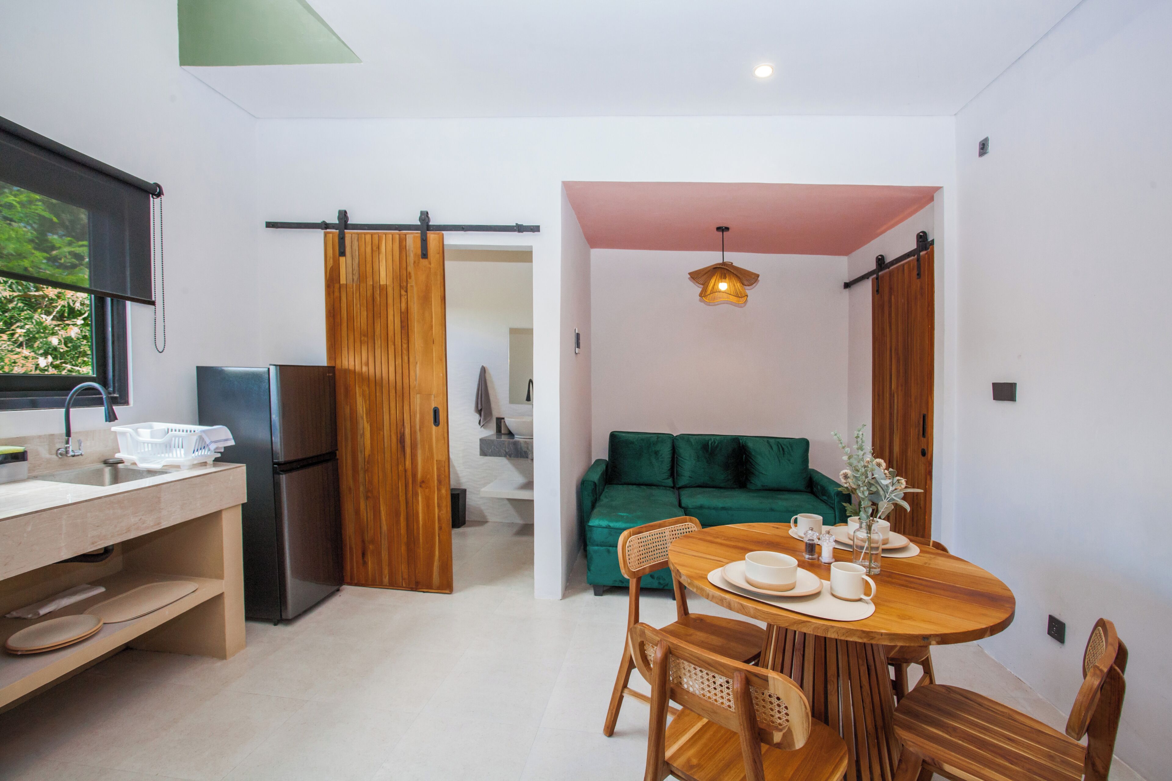 Eine moderne Küche mit Kühlschrank, Holzschränken und einem Essbereich mit Tisch und Stühlen.