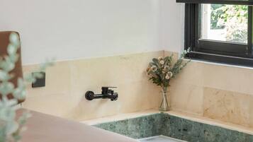 A bathroom with a bathtub, a window, and a small plant.