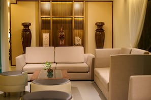 Una sala de estar moderna con un sofá, sillones, una mesa de centro y estatuas decorativas.