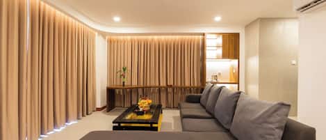 A modern living room with a sectional sofa, a glass coffee table, and a wooden sideboard.