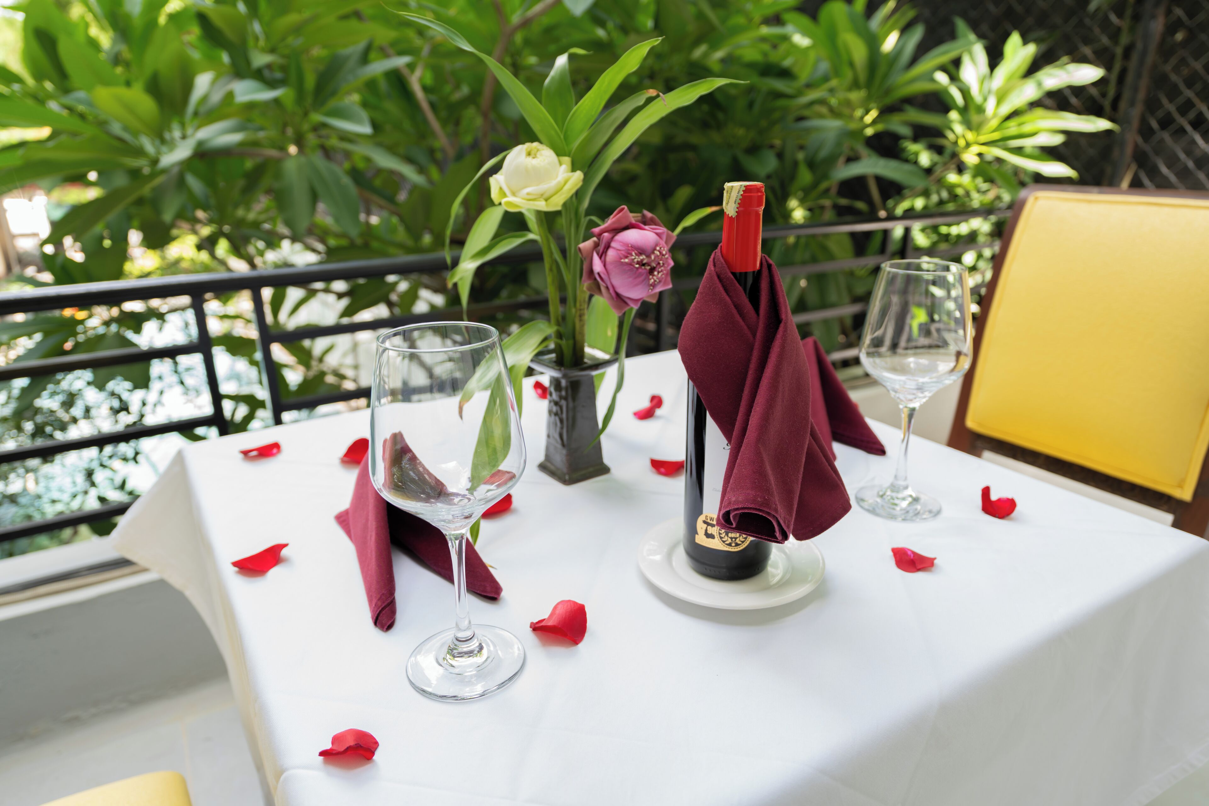 Una mesa dispuesta con copas de vino, una botella y un florero con flores.
