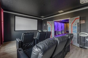 A cinema room with black leather reclining seats, a large blank screen, and a purple-lit corridor. - 14-bedroom house in Davenport close to Disney animal kingdom. (Davenport)