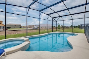 A swimming pool with a glass enclosure, a blue chair, and a view of residential buildings. - 14-bedroom house in Davenport close to Disney animal kingdom. (Davenport)