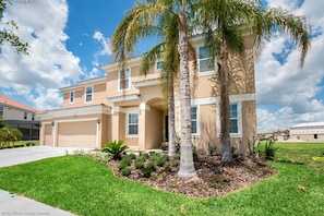 A two-story house with a garage, a well-maintained lawn, and a palm tree. - 14-bedroom house in Davenport close to Disney animal kingdom. (Davenport)