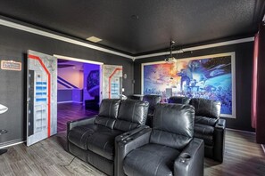 A home theater room with a large screen, leather reclining chairs, and a staircase leading to another level. - 14-bedroom house in Davenport close to Disney animal kingdom. (Davenport)