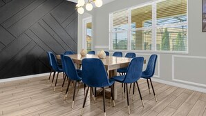 Un'area pranzo con un tavolo in legno, sedie rivestite di blu e una parete nera con motivi geometrici.