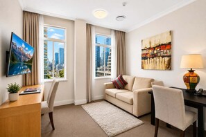 A hotel room with a flat-screen TV, a sofa, a desk, and a lamp. - Modern CBD Retreat | Walk to Shops & Dining (Brisbane)