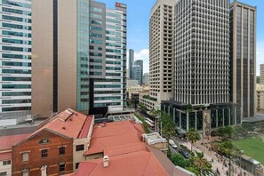 A cityscape with modern high-rise buildings, a mix of glass and concrete facades, and a central plaza with a statue. - Modern CBD Retreat | Walk to Shops & Dining (Brisbane)