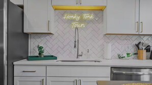Keittiössä on valkoiset kaapit, ruostumattomasta teräksestä valmistettu jääkaappi, pesuallas ja neonvalomainos, jossa lukee: ”Honkky Tonk Town”.