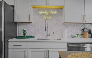 A kitchen with white cabinets, a stainless steel refrigerator, a sink, and a neon sign that reads 'Honkky Tonk Town.' - Luxury Nashville Vacation Rental with Resort-Style Amentities for a perfect stay (Nashville)