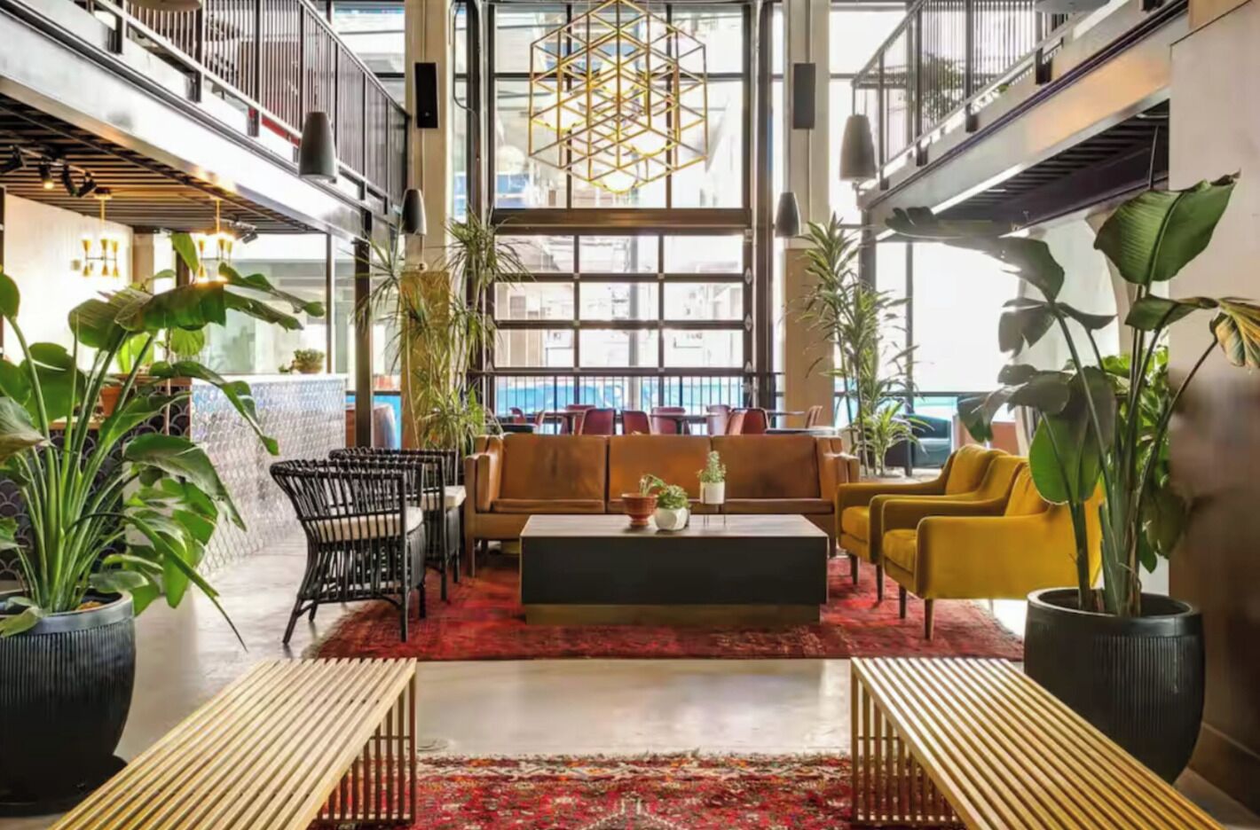Een ruime lobby met een centraal zitgedeelte, grote ramen en kamerplanten.