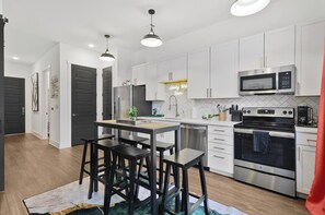 A modern kitchen with white cabinets, stainless steel appliances, and a central island with bar stools. - Luxury Nashville Vacation Rental with Resort-Style Amentities for a perfect stay (Nashville)