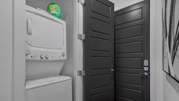 A laundry room with a washer and dryer, a dark door, and a painting on the wall.