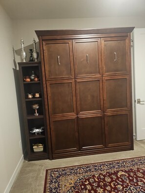 Ein großer, hölzerner Kleiderschrank mit mehreren Türen und eine Regalvorrichtung mit Dekorationselementen.