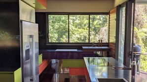 A modern kitchen with a large window, a ceiling fan, and a stainless steel refrigerator. - Luxury 3 bedroom Villa with Private Pool Views (Edge Hill)