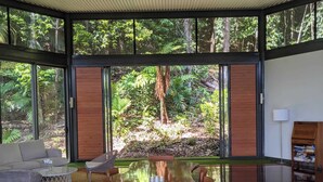 A spacious room with a large wooden table, a ceiling fan, and large windows offering a view of a forest. - Luxury 3 bedroom Villa with Private Pool Views (Edge Hill)