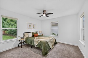 A bedroom with a bed, a ceiling fan, a window, and a small table. - Executive 3BR Home, King Suite, Near Hospitals & Historic Downtown Mansfield (Mansfield)