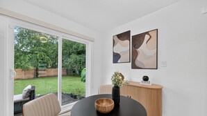 Una habitación moderna con una mesa redonda, un florero negro y arte abstracto en la pared.