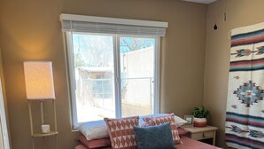 Ein Schlafzimmer mit einem Bett, einer Stehlampe, einem Fenster und einem Deckenventilator.