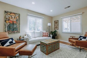 A living room with a sofa, two armchairs, a patterned ottoman, and a large painting on the wall. - Charming Retreat in ABQ's North Valley-close to Old Town and Balloon Fiesta Park (Albuquerque)