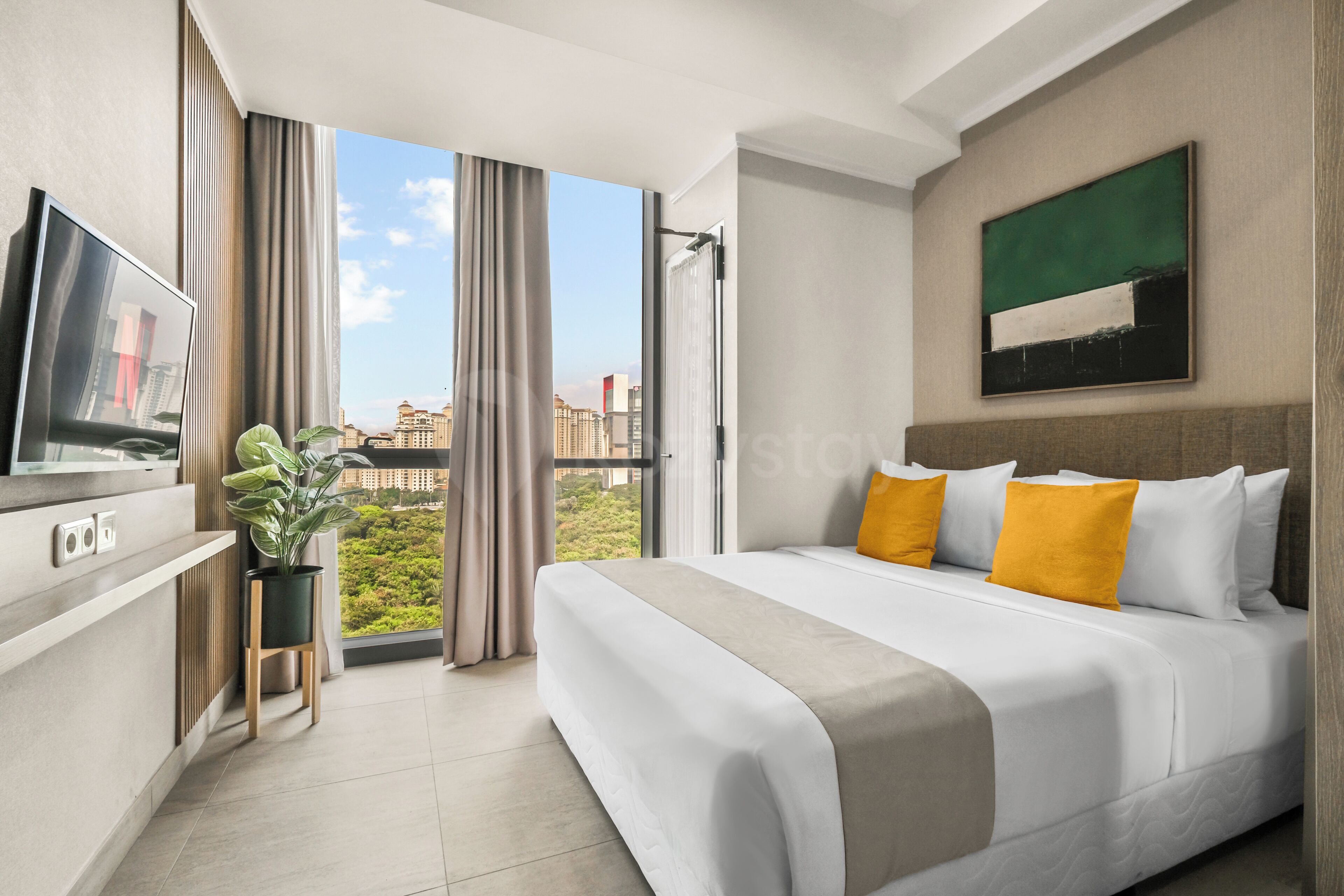 Une chambre d’hôtel avec un lit, une télévision, une plante en pot et une vue sur les immeubles.