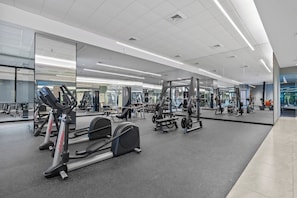 A gym with cardio equipment, weight machines, and mirrors on the walls. - Narela by Kozystay - Kemayoran (Central Jakarta)