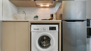 A compact kitchen with a built-in washer and refrigerator. - Narela by Kozystay - Kemayoran (Central Jakarta)